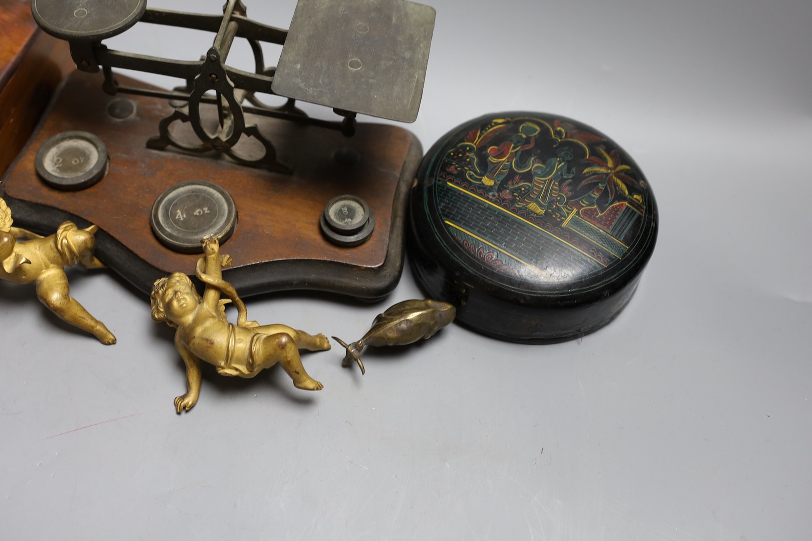 A set of three 19th century cast bronze cherubs, a set of lacquer coasters, a postal scale and a yew box